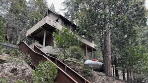 Une structure rustique en bois, dotée d’un escalier métallique menant à une plateforme.