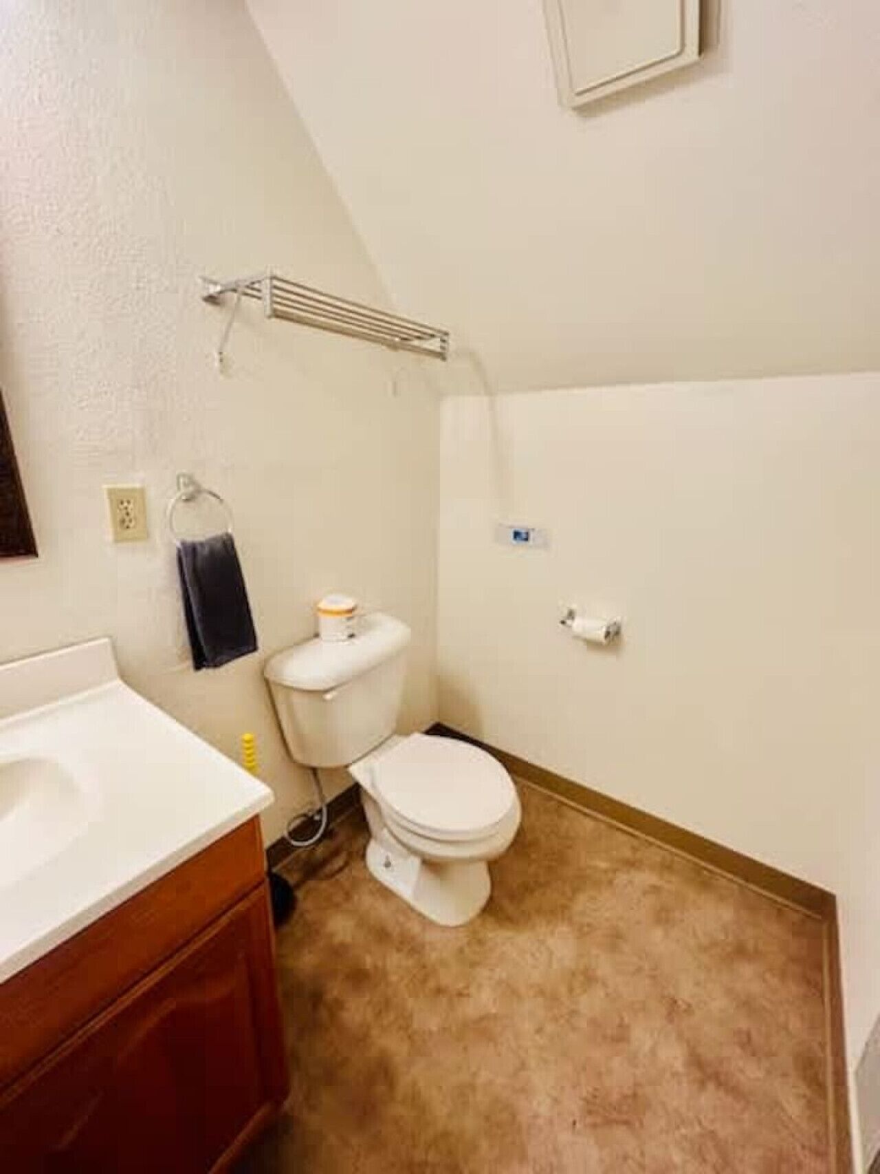Un baño pequeño con inodoro, lavamanos y barra para toallas.