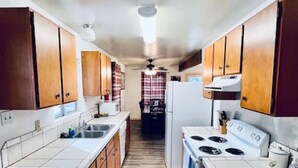 A narrow kitchen with wooden cabinets, a white stove, and a refrigerator.