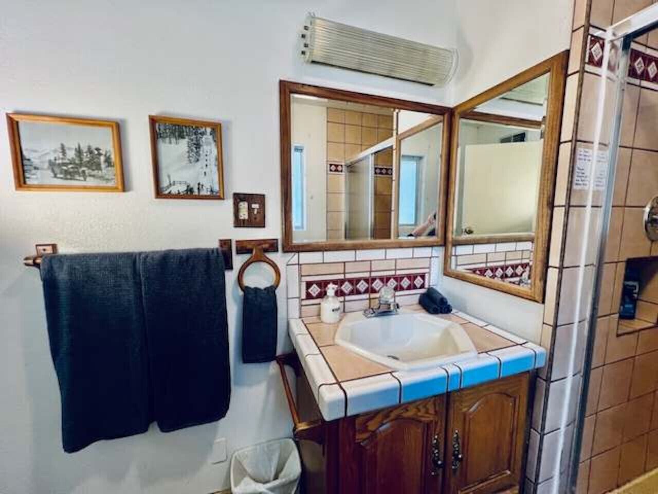 A bathroom with a sink, mirror, towel rack, and tiled walls.
