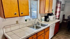 A kitchen with wooden cabinets, a sink, and a window.