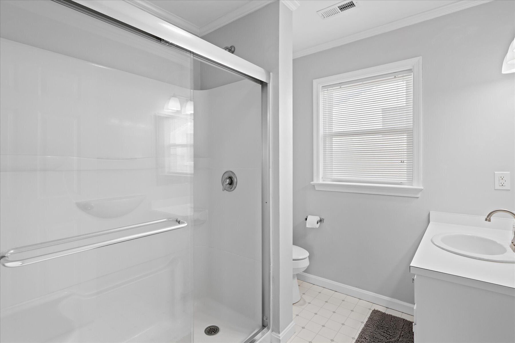Une salle de bain avec une douche à parois de verre, des toilettes et un lavabo avec un miroir.