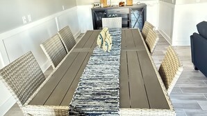 Ein Essbereich mit einem langen Tisch, Korbstühlen und einem Deckenventilator.