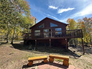 A wooden cabin with a deck, two benches, and a clear view of the surrounding forest. - Serene and Peaceful Cabin 50 mins to Breckenridge (Jefferson)