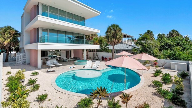 A modern two-story house with a swimming pool, outdoor seating, and tropical landscaping. - Casa Floridita by Duncan Real Estate (Anna Maria)