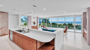 A modern kitchen with a large island, a dining area with a view of the ocean, and a cozy seating area with a view. - Casa Floridita by Duncan Real Estate (Anna Maria)