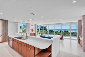 A modern kitchen with a large island, a dining area with a view of the ocean, and a cozy seating area with a view. - Casa Floradita by Duncan Real Estate (Anna Maria)