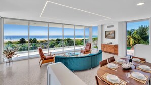 A modern living room with a large glass wall offering a view of the beach. - Casa Floridita by Duncan Real Estate (Anna Maria)