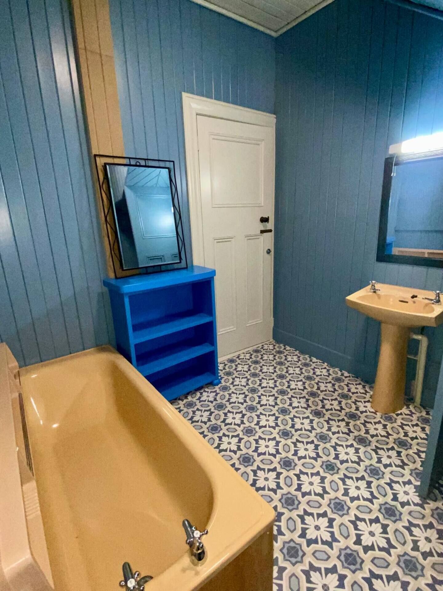 A bathroom with a bathtub, a sink, a mirror, and a door.
