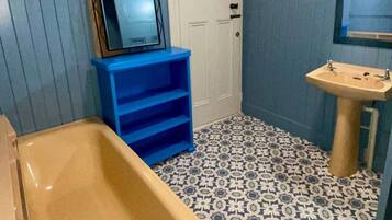 A bathroom with a bathtub, a sink, a mirror, and a door.