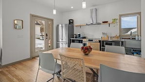 Una cocina moderna con electrodomésticos de acero inoxidable, una mesa de comedor de madera y vistas al exterior.