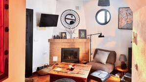 Ein gemütliches Wohnzimmer mit Kamin, einer Couch, einem Couchtisch und einem an der Wand montierten Fernseher.