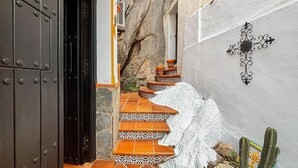 Eine enge Treppe mit Terrakotta-Stufen, die zu einer Tür mit schwarzem Rahmen führt.