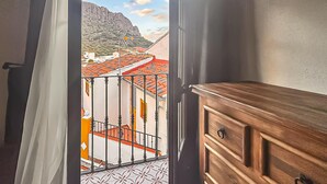 Ein Zimmer mit Balkon mit Blick auf eine Stadt mit roten Dächern und einem Berg im Hintergrund.