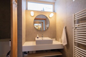 A modern bathroom with a white sink, a round mirror, and a towel rack. - Chihiro Niseko (Kutchan)