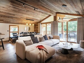 A modern living room with a sectional sofa, dining area, and large windows. - Chalet Ritord - Vanoise mountains and private sauna - OVO Network (Pralognan-la-Vanoise)