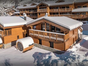 Un chalet en bois doté de plusieurs balcons et dont le toit est recouvert de neige.