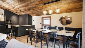 Eine moderne Küche mit dunklen Schränken, einem Holzespeisetisch für sechs Personen und einem großen Spiegel an der Wand.