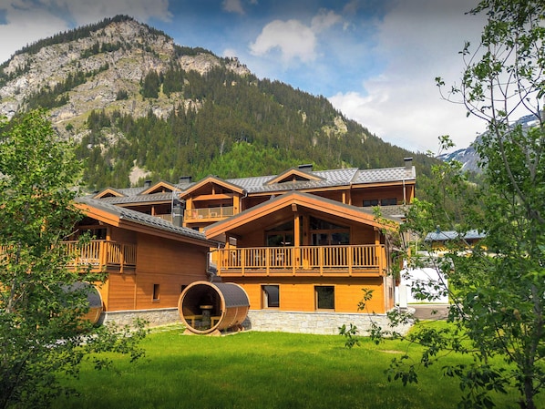 Un chalet en bois doté d’un balcon, d’une cuve en pierre et surplombant un paysage de montagne.