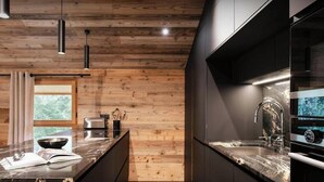A modern kitchen with wooden ceiling, dark cabinetry, and a marble countertop. - Chalet Rongbuk - Unspoiled mountain landscapes and sauna - OVO Network (Pralognan-la-Vanoise)