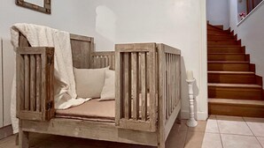 Puinen sänky, jossa on valkoinen peitto ja tyynyjä, valkoinen seinä ja valkoisella kaiteella varustetut portaat.