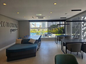 Un espace de travail partagé moderne, doté d’une grande fenêtre, d’un canapé et d’un coin repas.