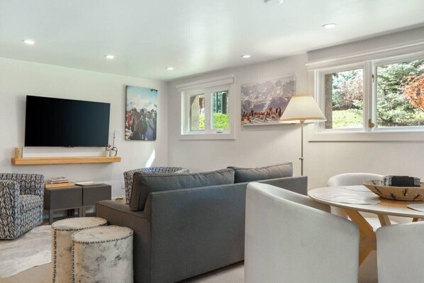 A modern living room with a grey sofa, a patterned armchair, a flat-screen TV, and artwork on the walls. - Vail Condo - Pet Friendly & Steps to Ski Lift (Vail)