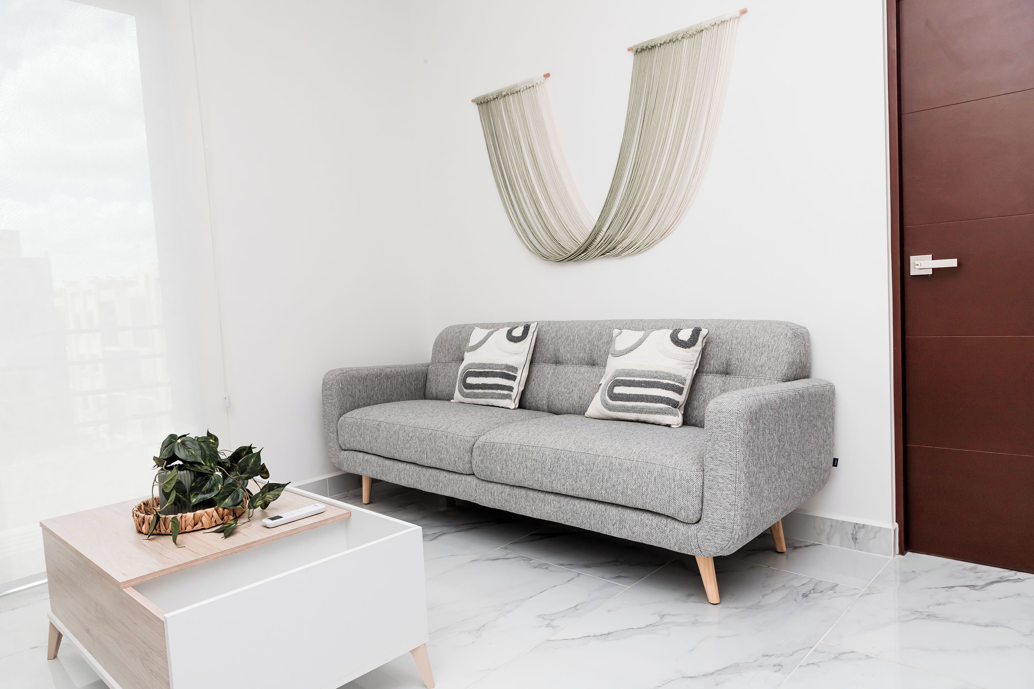 Een moderne woonkamer met een grijze bank, een witte salontafel en een hangmat.