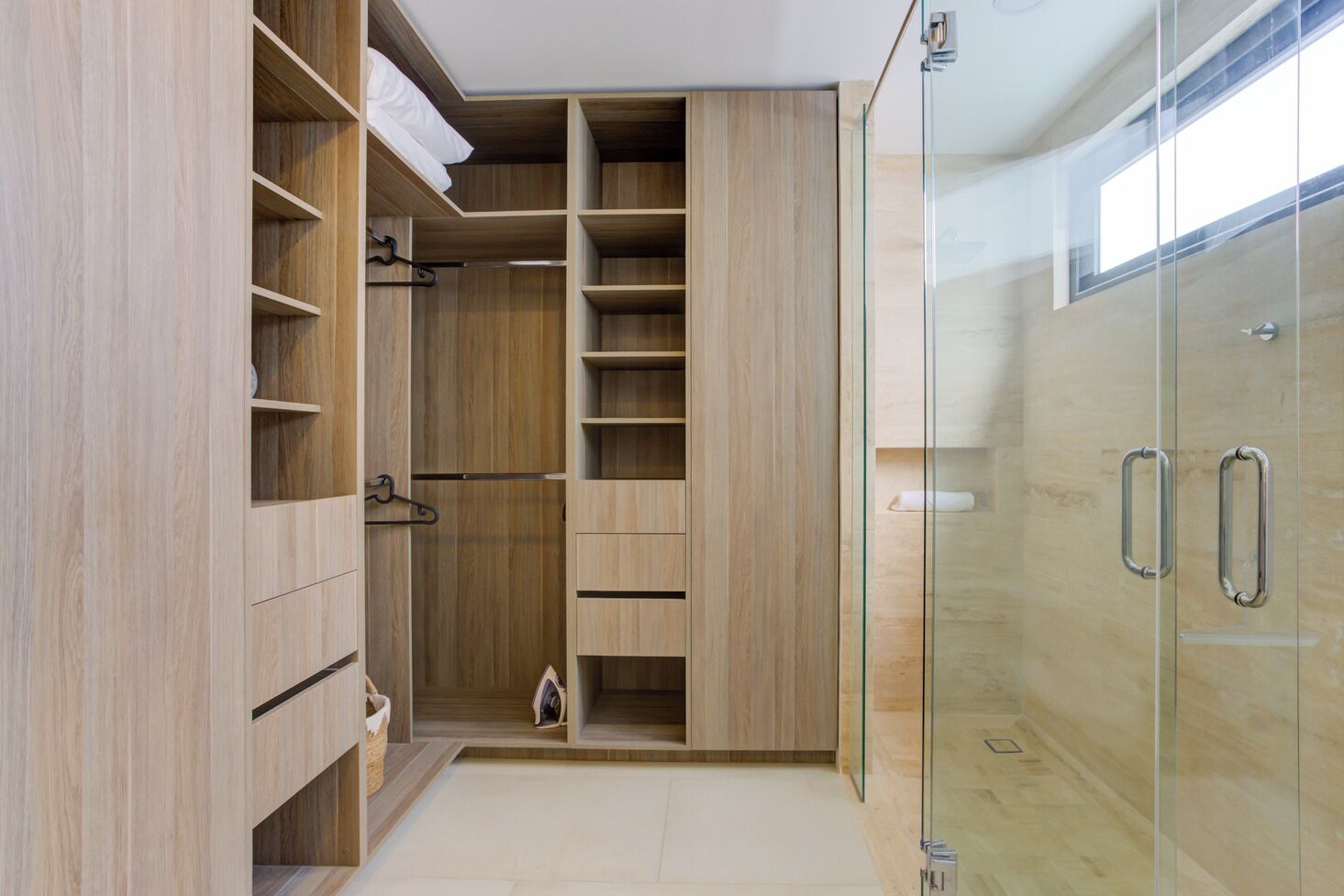 Ein modernes Badezimmer mit bodengleicher Dusche, einem großen Holzwaschtisch mit mehreren Ablagen und einem Duschbereich mit Glastrennwand.