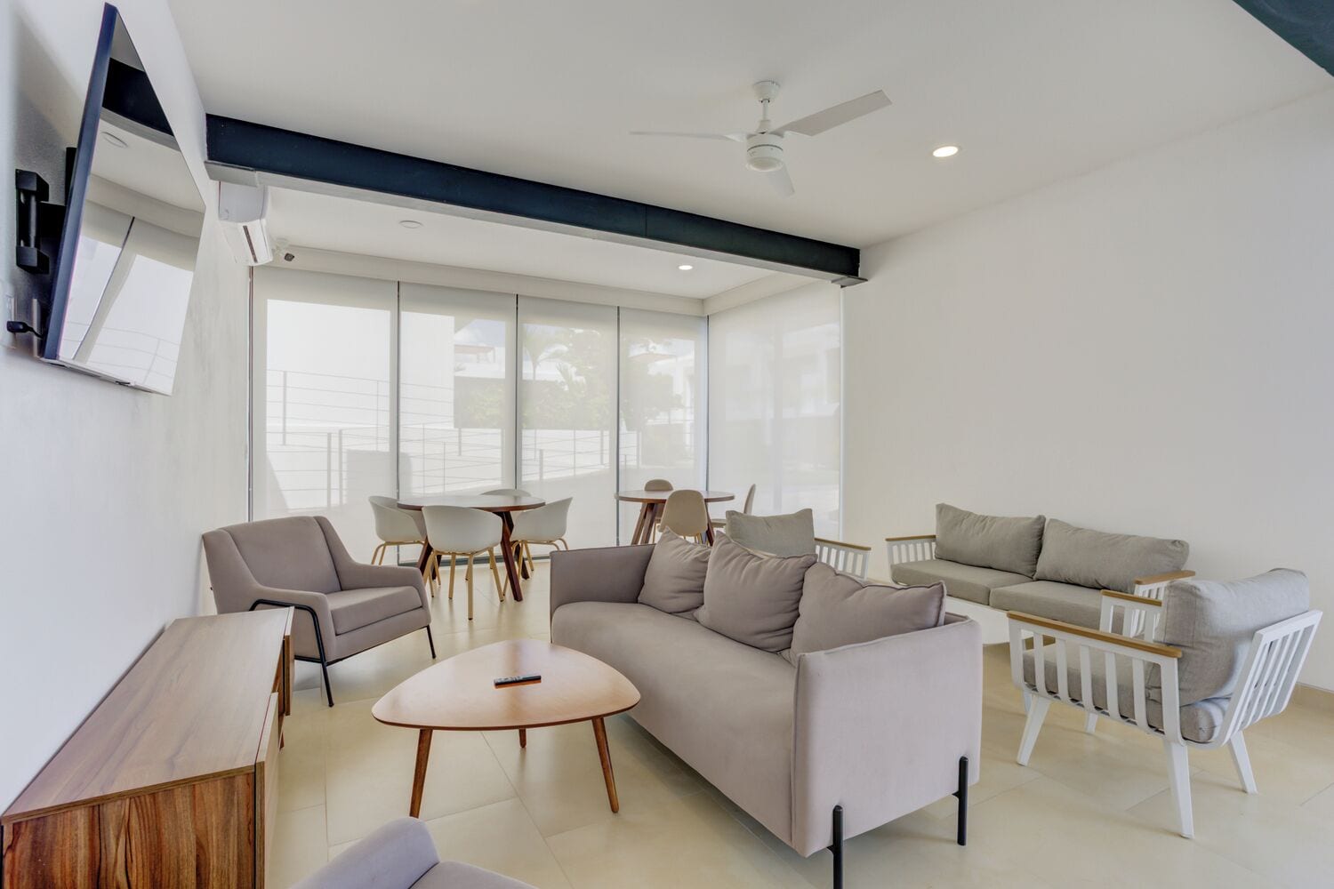 A modern living room with a sectional sofa, a coffee table, and a dining area with chairs and a table.