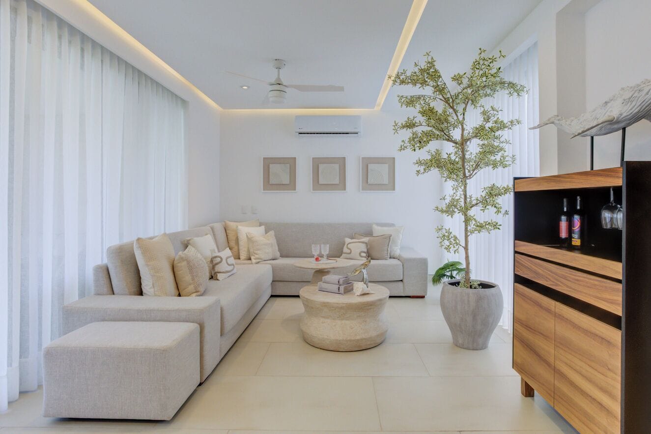 Una sala de estar moderna con un sofá seccional, una mesa de centro redonda, una planta en maceta y un mueble de madera.