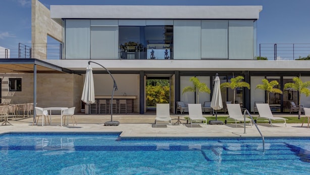A modern hotel with a swimming pool, lounge chairs, and umbrellas. - Vista Natura-Luxury Home Near the Beach (Nuevo Nayarit)