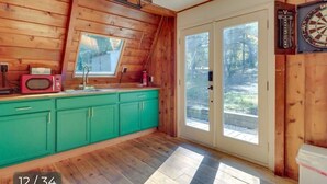 A wooden interior with a kitchen area, including green cabinets and a microwave. - Lovers Edge Romantic A-Frame: Hot Tub, Sauna & Fire Pit (East Stroudsburg)
