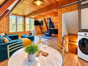 Una habitación acogedora con un sofá, una mesa con una planta, una botella de vino y copas.