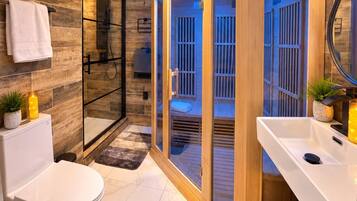 A modern bathroom with a bathtub, shower, and a glass-enclosed sauna area.