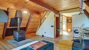 A wooden interior with a wood stove, staircase, and a laundry area. - Lovers Edge Romantic A-Frame: Hot Tub, Sauna & Fire Pit (East Stroudsburg)