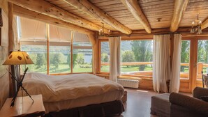 Une chambre dans une cabane en bois, avec un grand lit, un petit canapé et une vue sur un lac.