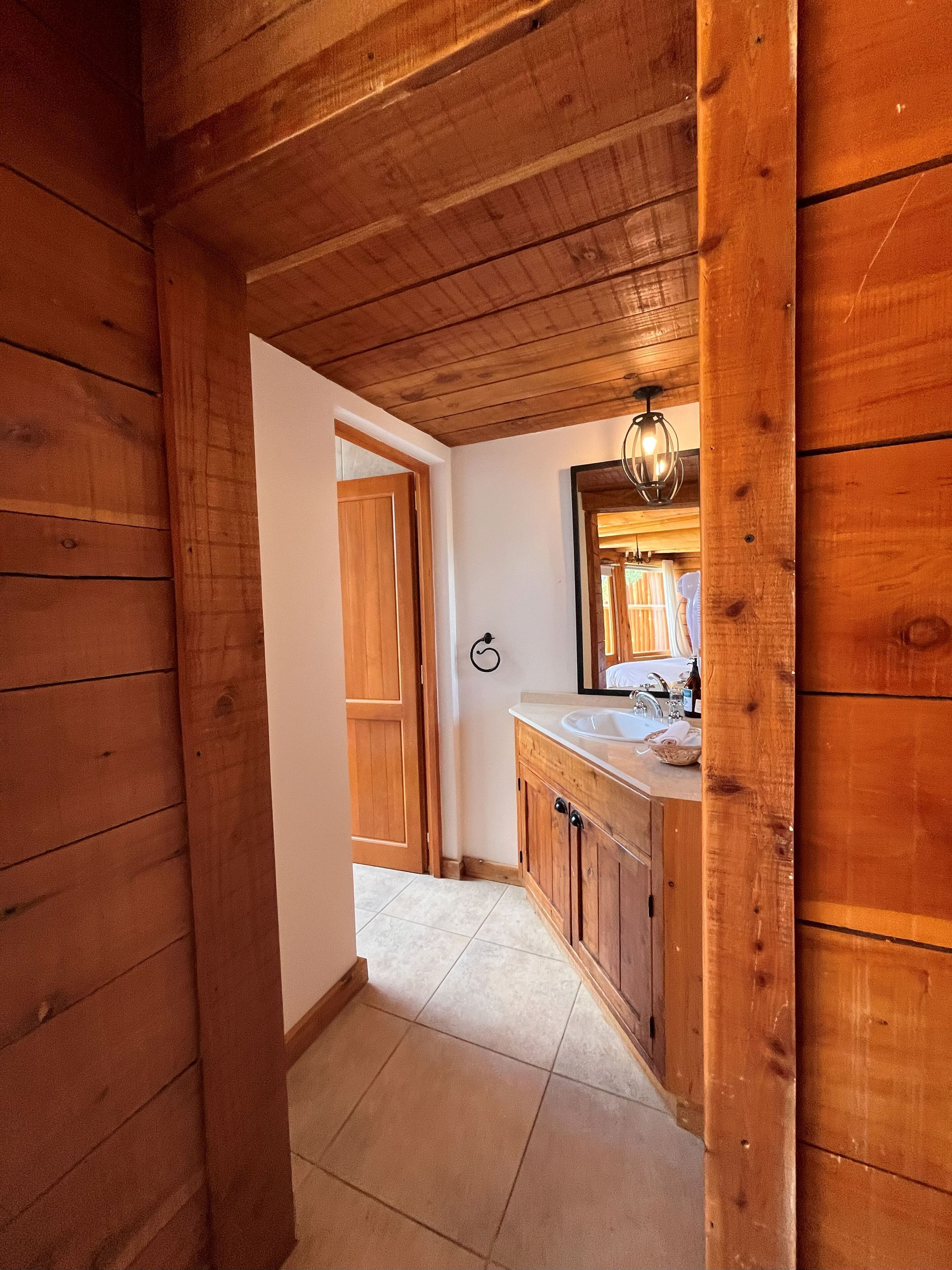 Un interior de madera con un baño que incluye un lavabo, un espejo y armarios de madera.