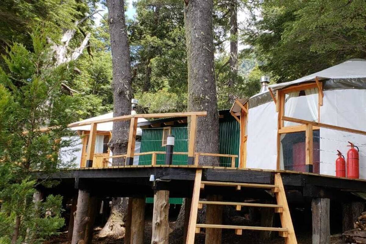 A treehouse with a wooden deck and a covered sleeping area.
