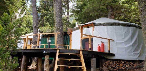 Una casa en el árbol con terraza de madera y un espacio cubierto para dormir.