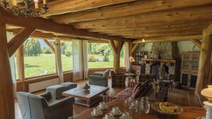 Un intérieur de chalet chaleureux avec un coin repas, des sièges et une vue sur l’extérieur.