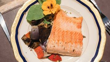 A plate with salmon, vegetables, and a flower.