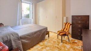 Ein Schlafzimmer mit einem Bett, einem Sessel, einem Kleiderschrank und einer Heizung.