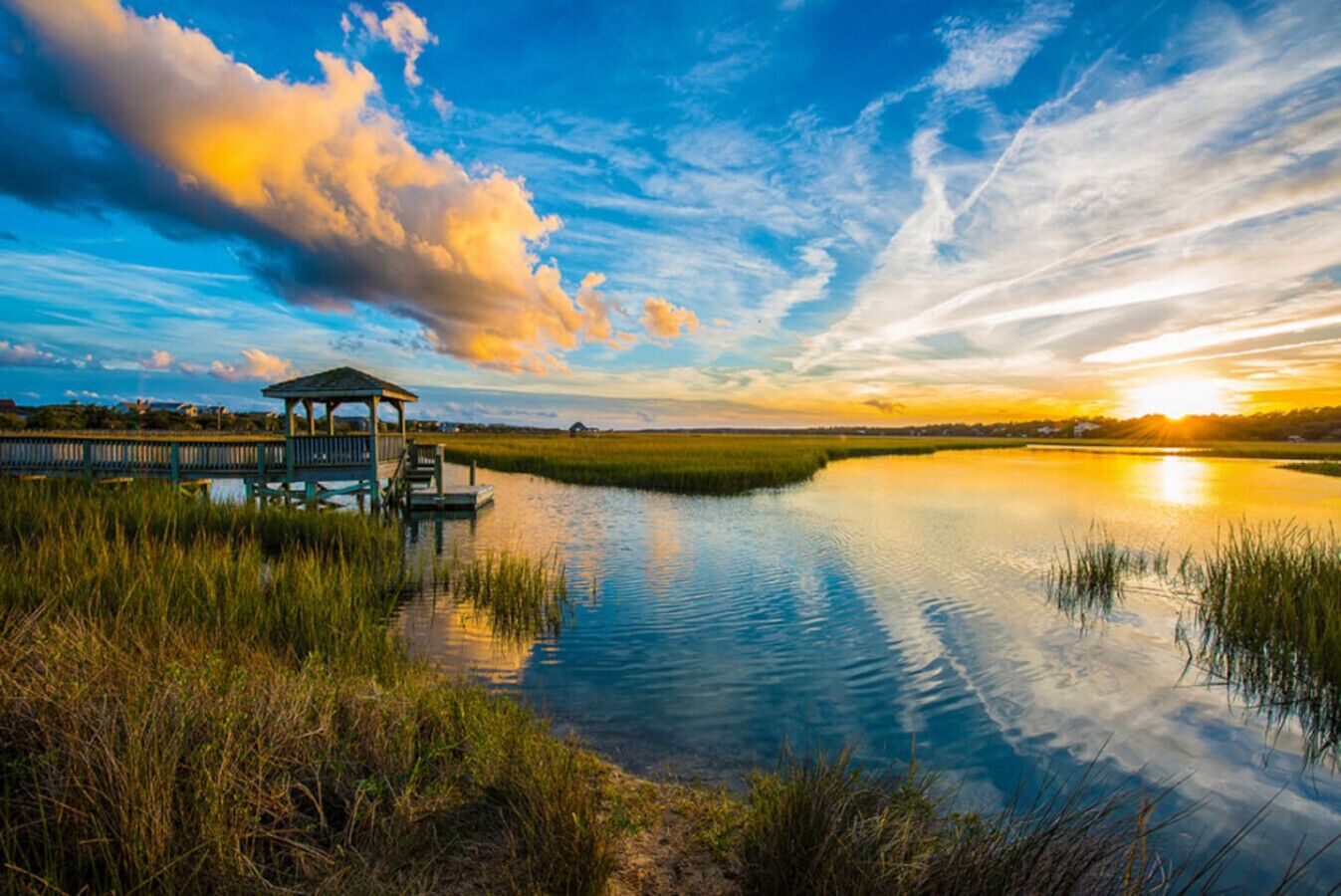 Un paysage paisible au bord d’un lac, avec un kiosque, une eau calme et un coucher de soleil.