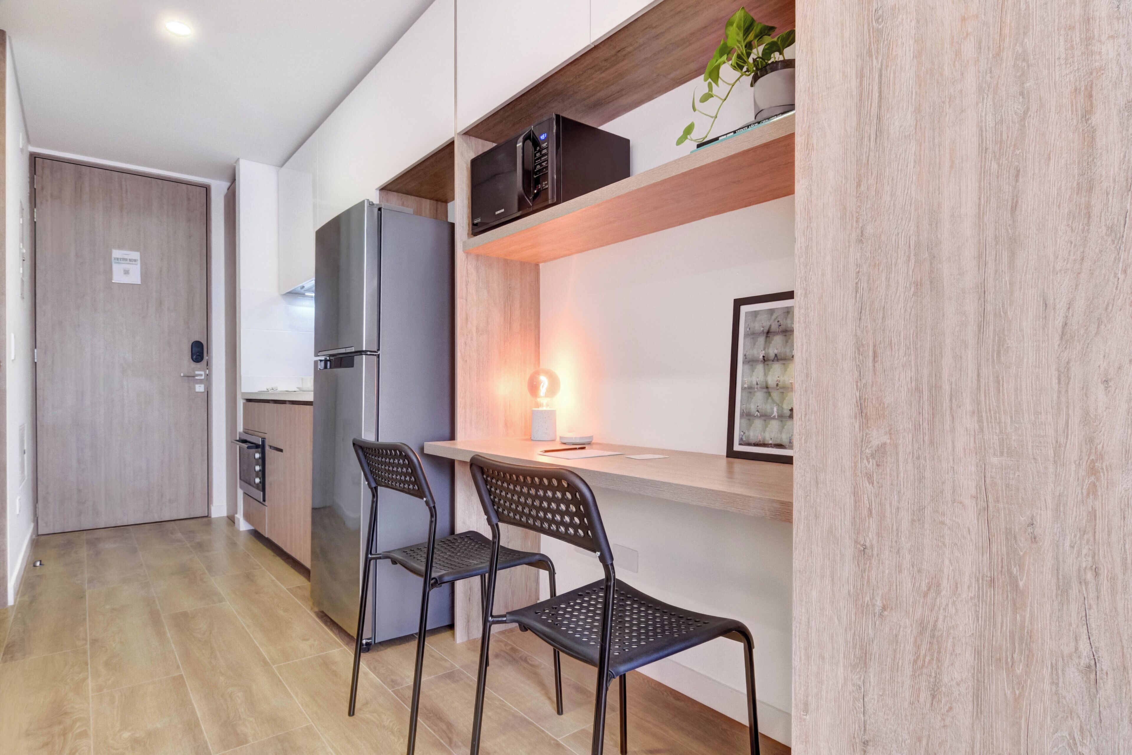 A modern kitchen with a built-in refrigerator, a wooden countertop, and two black chairs.