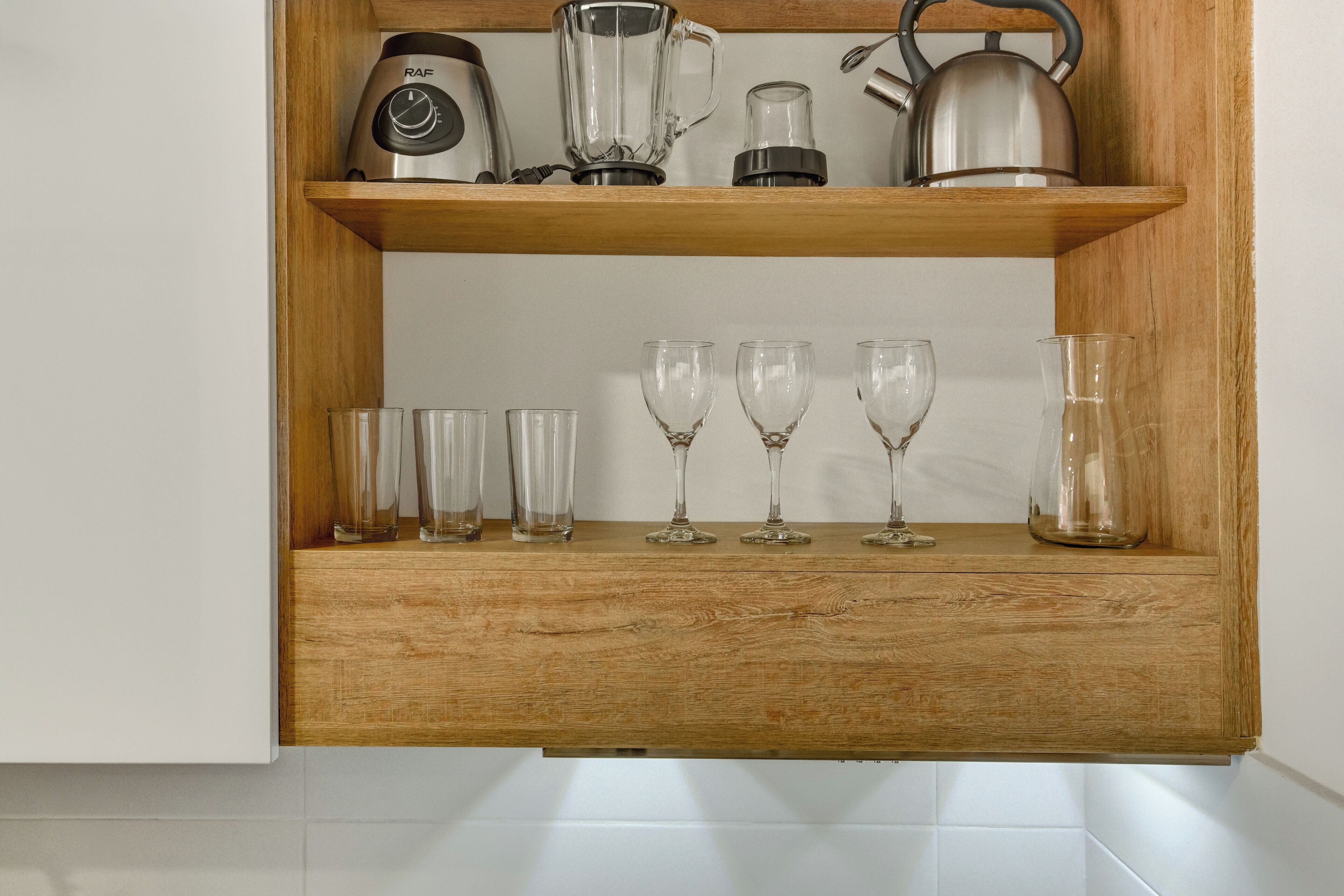 A wooden shelf with kitchen appliances and glassware.