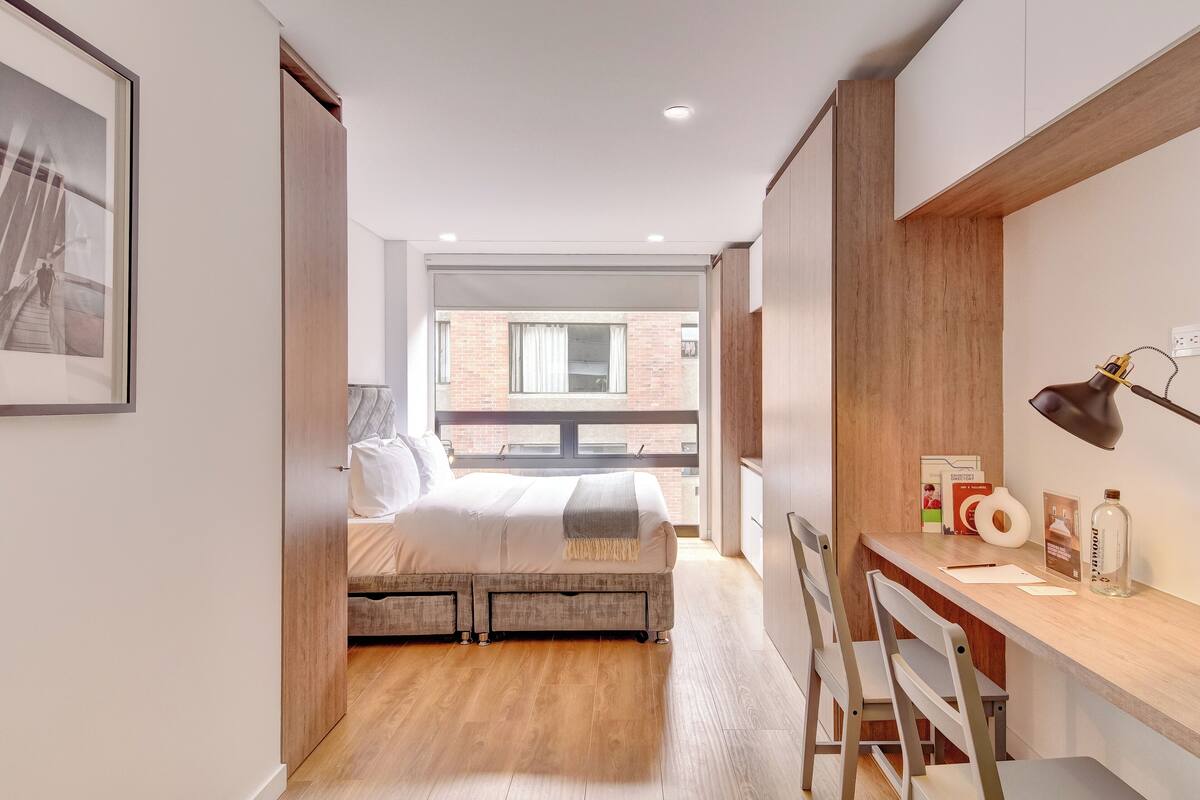 A bedroom with a bed, a desk, and a chair.