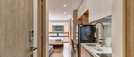 Una cocina moderna con refrigerador, lavamanos y una zona de comedor con sillas.