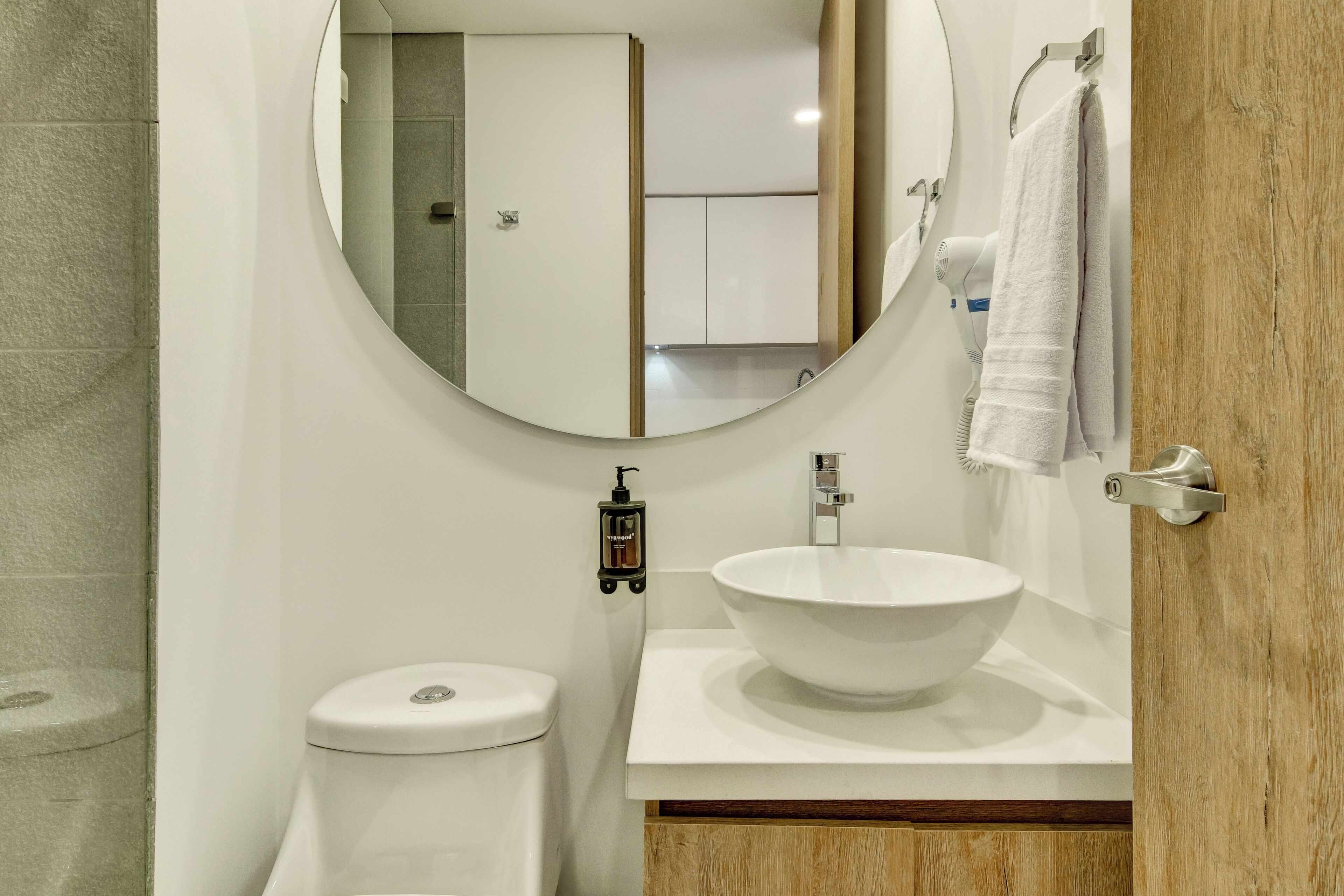 A bathroom with a toilet, a sink, a mirror, and a towel rack.