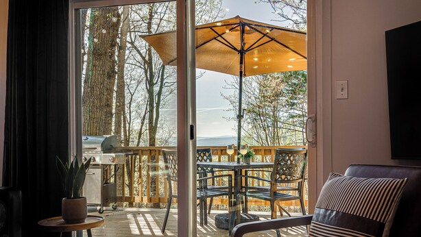 Een kamer met een schuifglasdeur die uitkomt op een terras met een tafel, stoelen en een grote parasol.